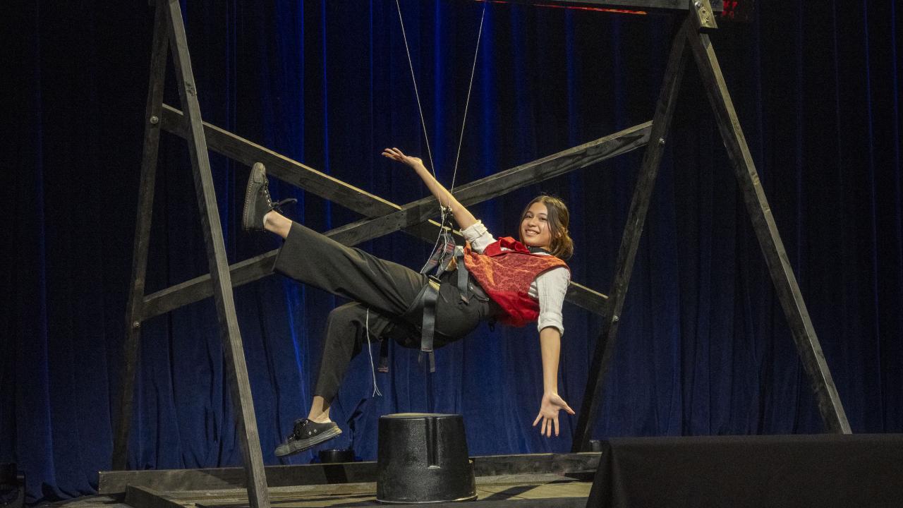 A girl hanging from thin string attached to a beam