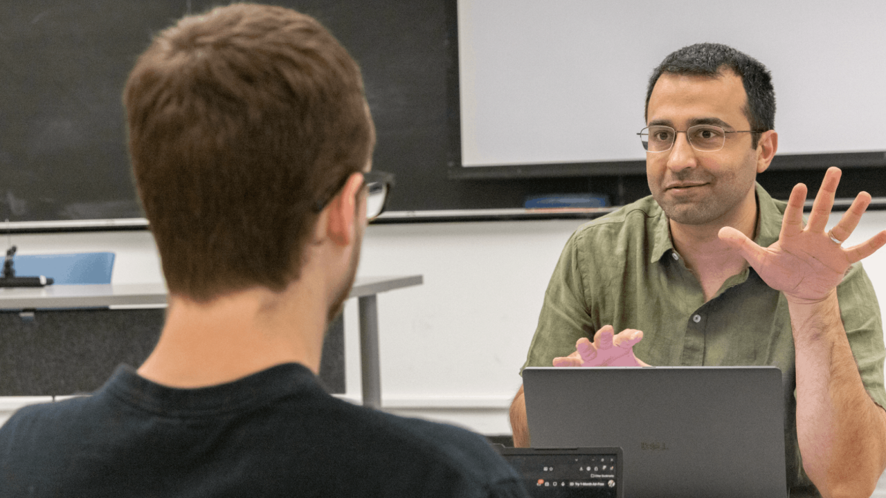 Instructor in a green shirt in discussion with a student